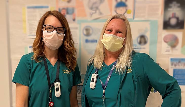 Two speech pathologists post for a photo in their green scrubs. 