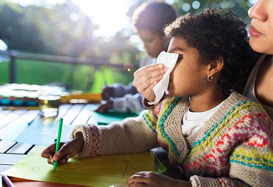 Adult helping a school child blow their nose