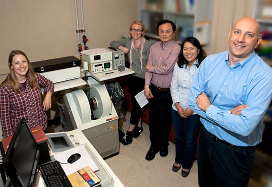 A group of people stand in a room next to a machine.