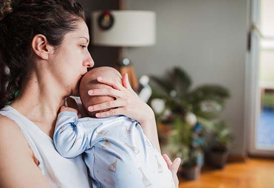 Mom in the hospital kissing baby on the head