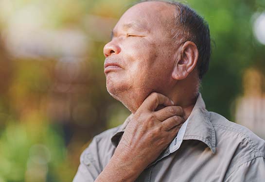 Older male patient holding his throat