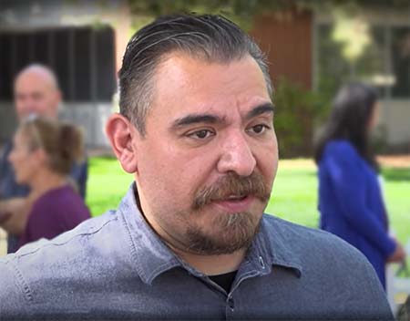 Daniel Cuevas wearing blue shirt with people in the background