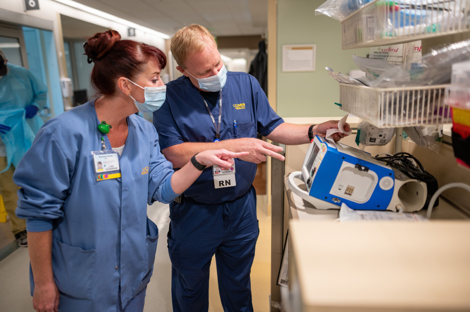 Len Sterling and another nurse, both in scrubs, point to a digital monitor in the burn center   