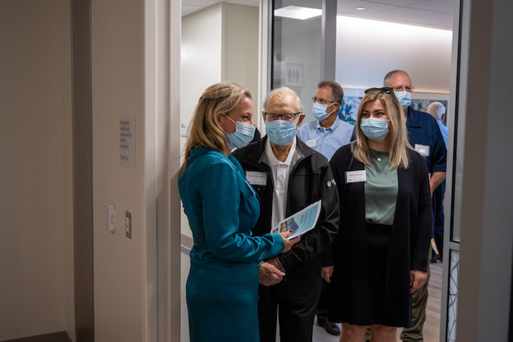 A group of five people wearing masks stand at the entrance to a room. 