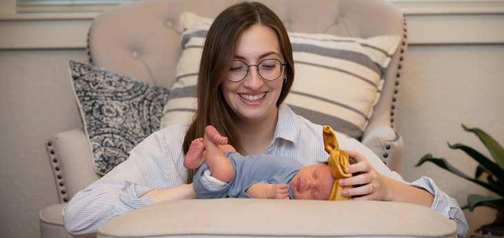 Emily looking down at baby Robbie laying on a pillow