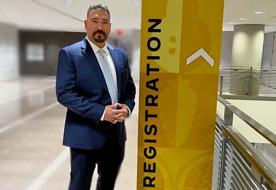 Santana Diaz wearing a suit standing next to a sign