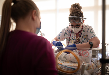 NICU nurse caring for a baby while mom watches