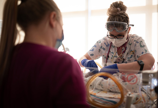 Nurse checking a NICU baby while mother watches