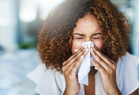 Woman sneezing into a tissue