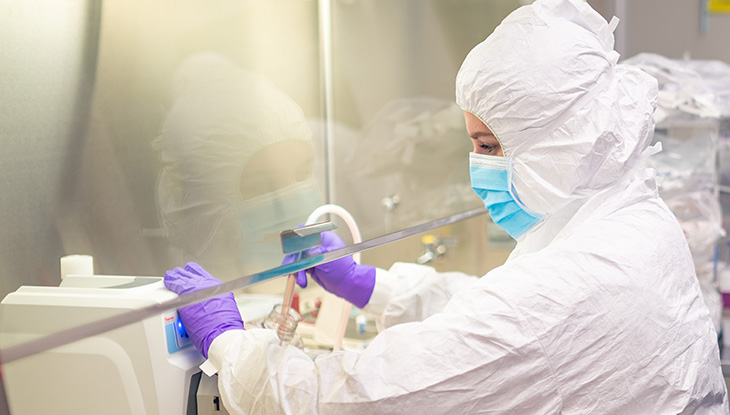 An individual in full protective gear working in the Good Manufacturing Practice facility