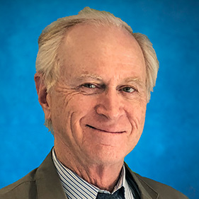 Man with gray hair, blue tie, striped shirt and gray coat with blue background