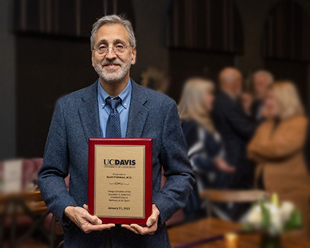 A smiling middle-aged man wearing a blue suit holds a plaque in his hands. 