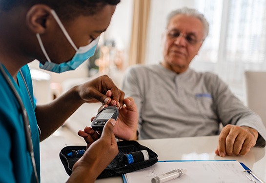 Nurse pricking finger of patient to check their blood sugar