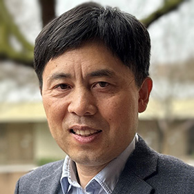 A man with dark hair standing outside