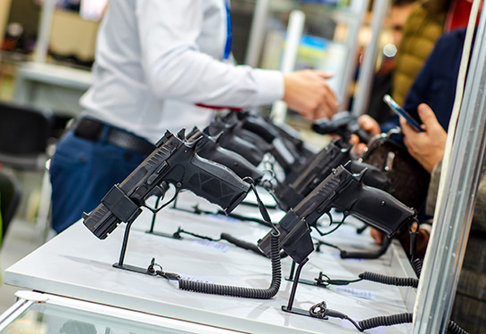 A gun display case with people standing nearby.