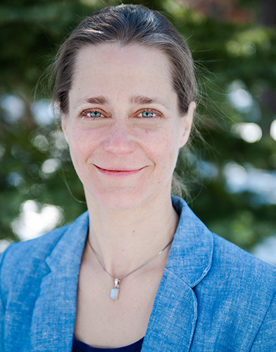 A formal headshot of a woman with her hair pulled back and wearing a light blue blazer and blue shirt. 