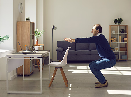 A man doing squats next to his desk