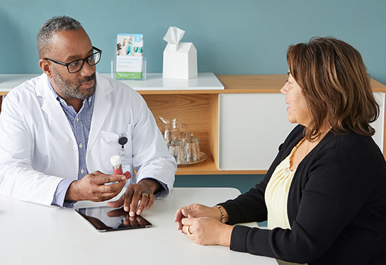 Doctor holding inhaler and showing it to patient sitting at table