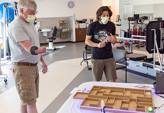 Right arm amputee performs a task with a bioengineering device on his right limb. 