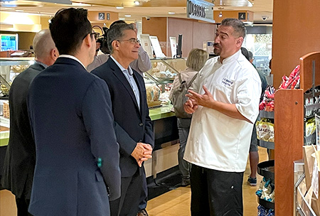 Three men stand together in a cafeteria.