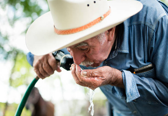 Man drinking from a hose