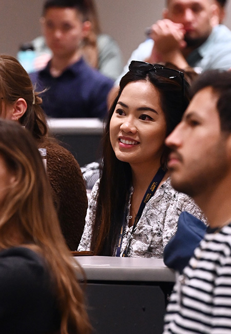 Young woman sitting in lecture hall surrounded by medical students