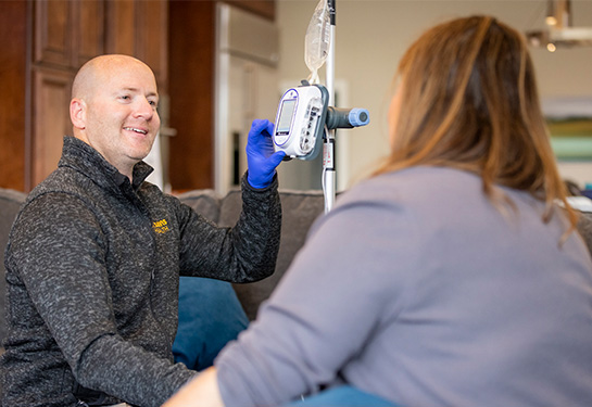 Man sitting couch with infusion machine speaking to a woman