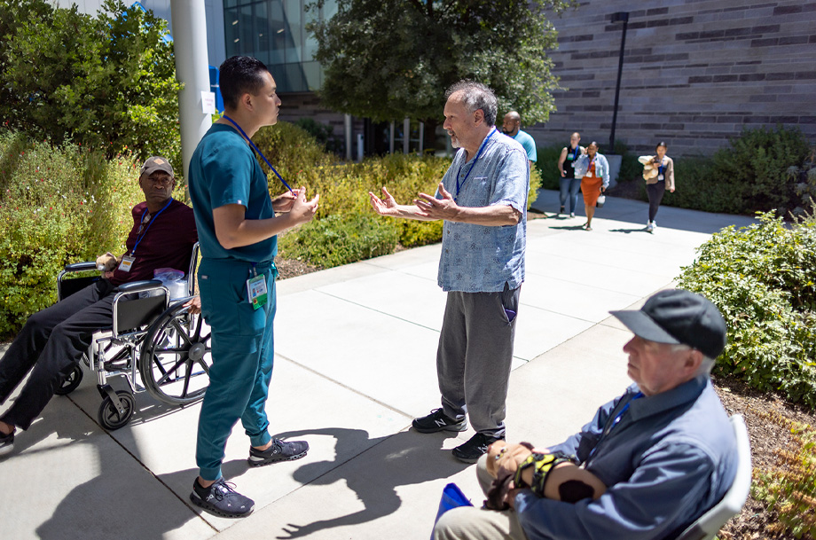 Nursing student stands with outstretched hands talking to pleading evacuee