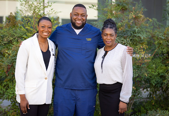 Aron King stands in center with arms around shoulders of Calene Roseman, left, and DaJanae Gresham-Ryder