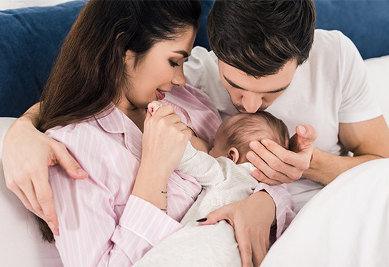 mom breastfeeding with dad kissing top of baby's head