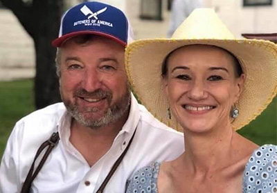 Man wearing baseball hat and woman with blue dress and hat