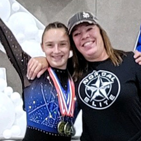 Julia and her mom in front of a USA sign in a gym