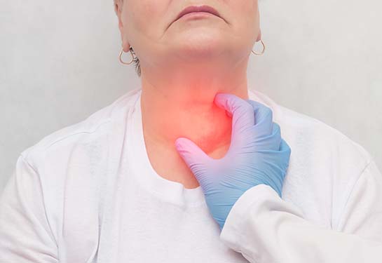 Person wearing white shirt having front of neck felt by hand wearing blue glove