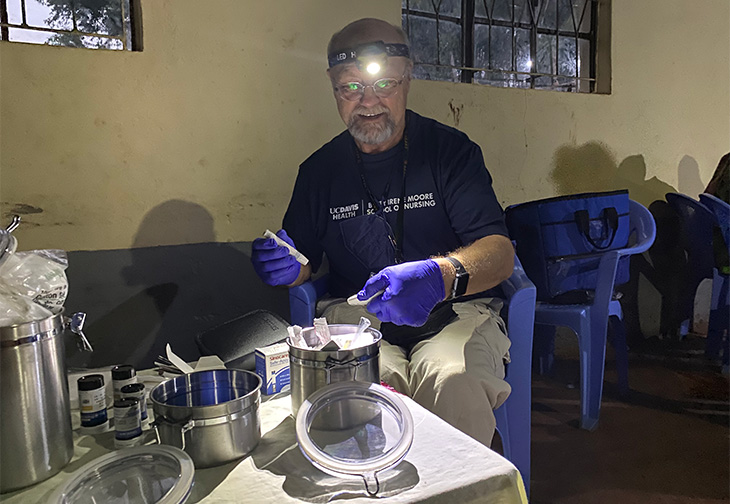 Man wearing blue shirt and light on his head checking blood, sugar levels