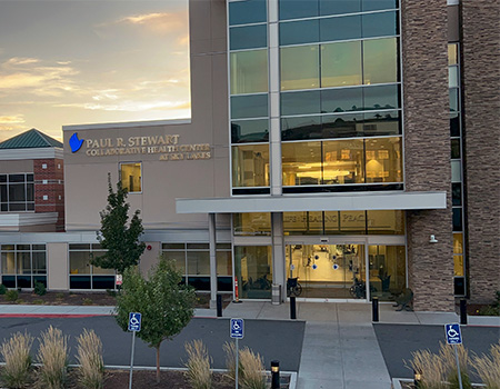 Photo of a modern, three-story medical clinic with façade full of windows and pillars made of brick 