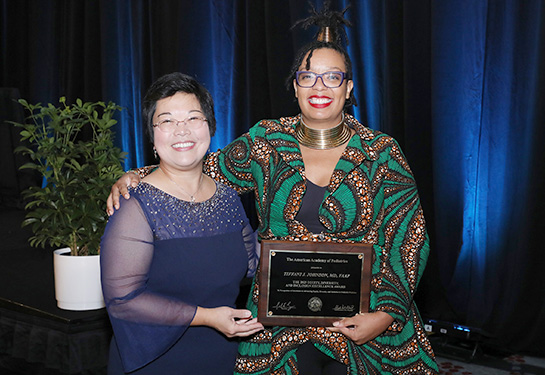 Two women smiling and holding a plaque