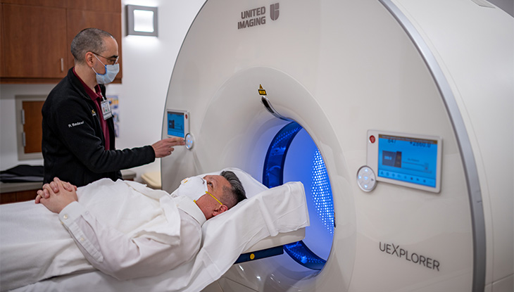 Woman lying head-first on large medical scanner shaped like a cone. 