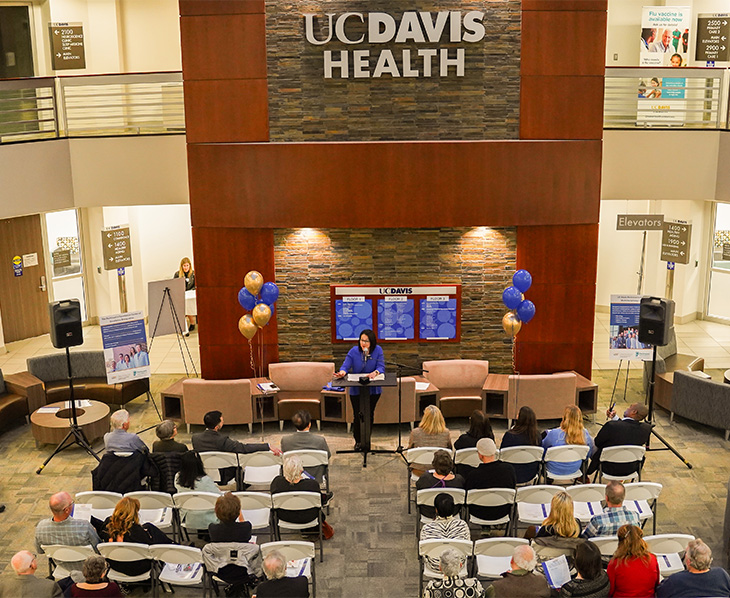 Woman in blue speaks to an audience at a podium