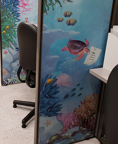 A colorful sea life panel surrounds a blood draw station with large chair. 