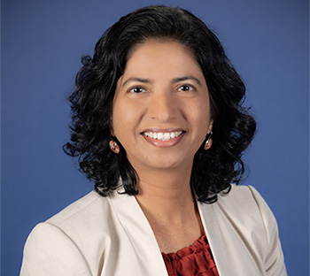 Smiling woman with shoulder length wavy black hair.