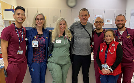 Seven people standing arm in arm smiling.