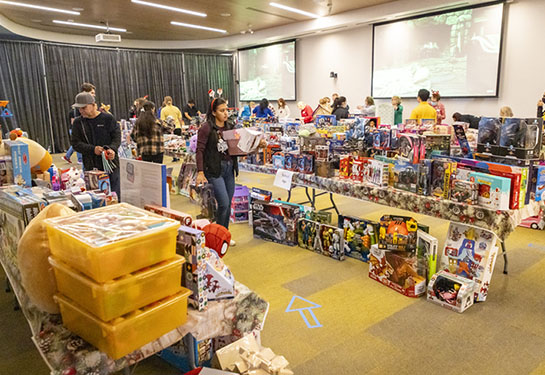 A handful of people peruse through a conference room where hundreds of new toys crowded the tables and floor.