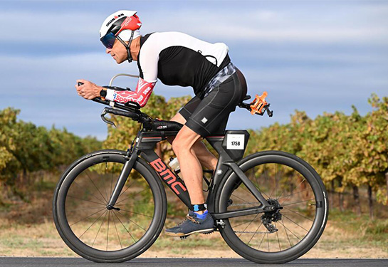 Man riding racing bike with green orchard of trees in the background