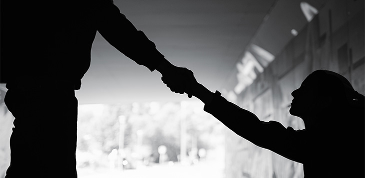 Someone is giving a helping hand to woman in need sitting on a dark street