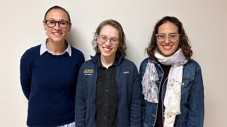 Three people wearing glasses stand shoulder-to-shoulder smiling