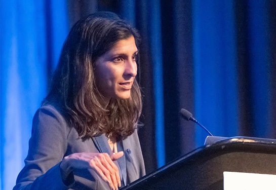 A woman with dark hair standing behind a podium