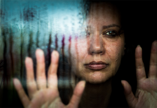 Woman with her hands on the window looking out