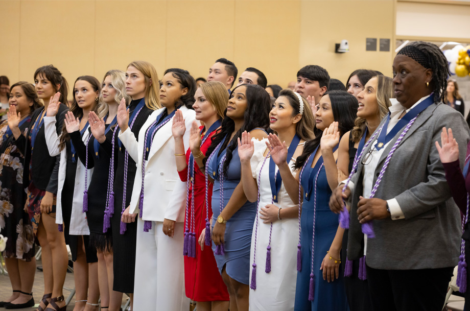 Nursing students stand side-by-side with palms raised to recite their pledge