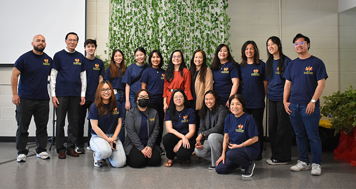 A group of people from the VMMS event. Dr. Oanh Meyer is in a red dress, standing in the middle of 12 individuals in the back. Five people are kneeling in the front.