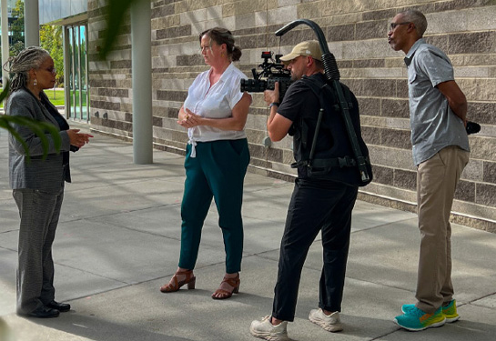 Woman facing cinematographer&#x2019;s camera being interviewed by film crew